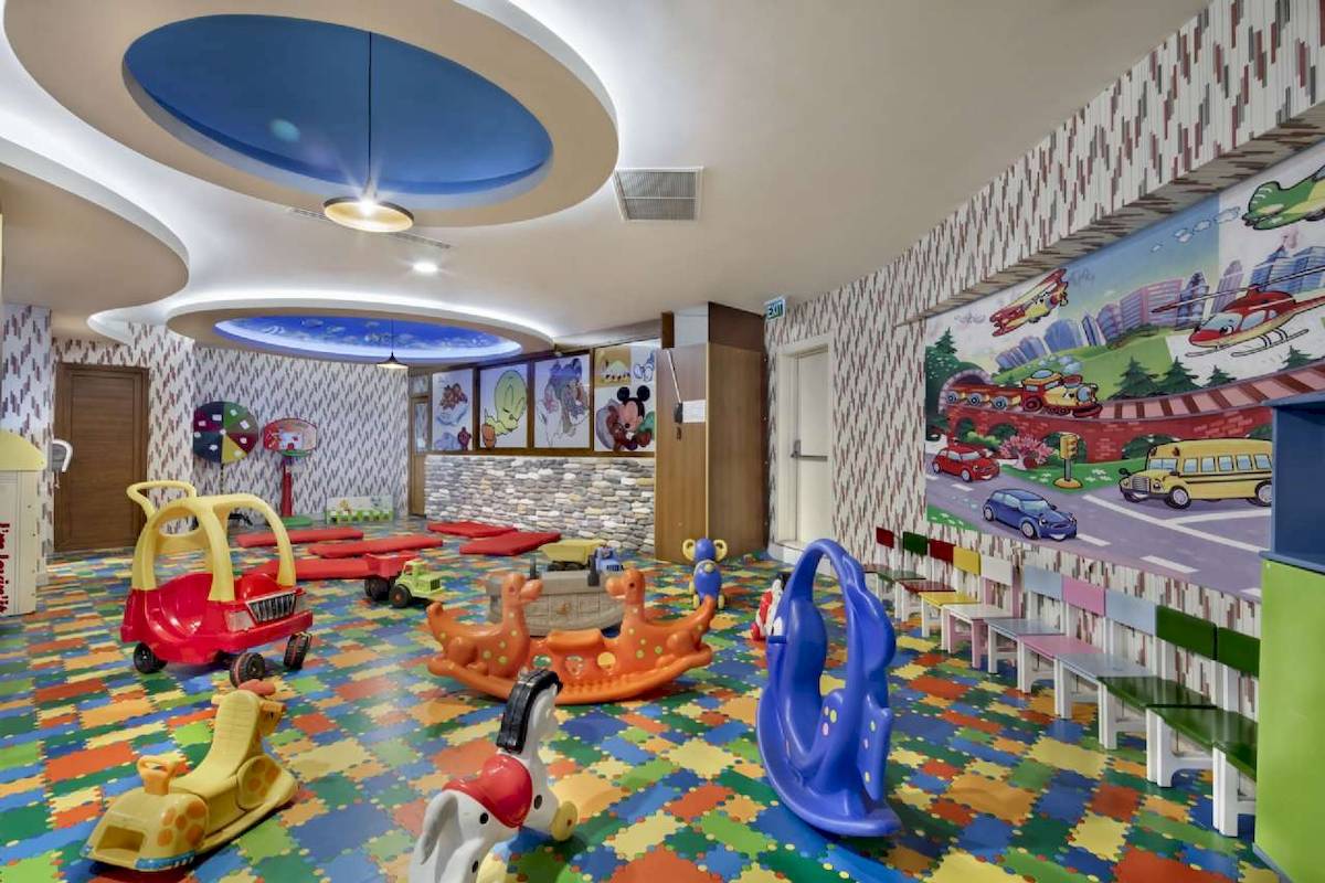 Kinderspielzimmer im Granada Luxury Hotel Okurcalar mit bunten Puzzle-Boden, Spielfahrzeugen und Wandmalereien.