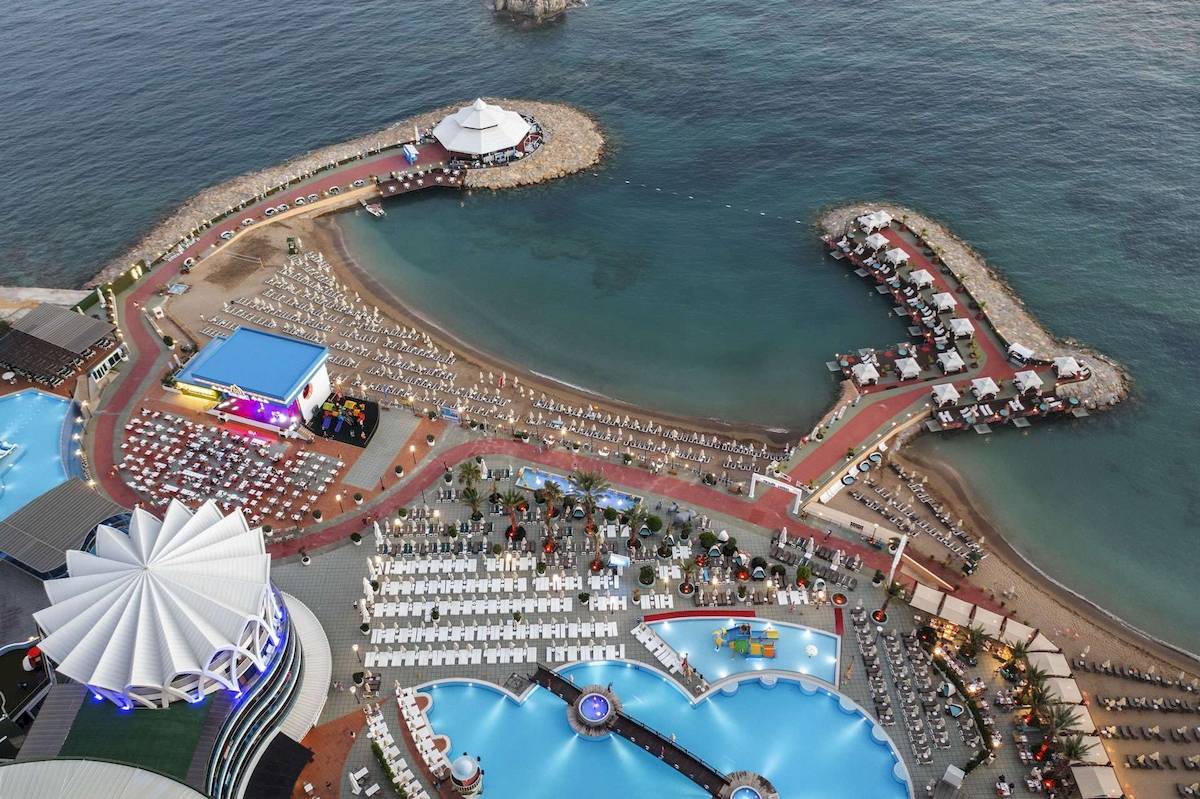 Luftaufnahme des Granada Luxury Okurcalar Hotels mit Strand, Pools und Pavillons.