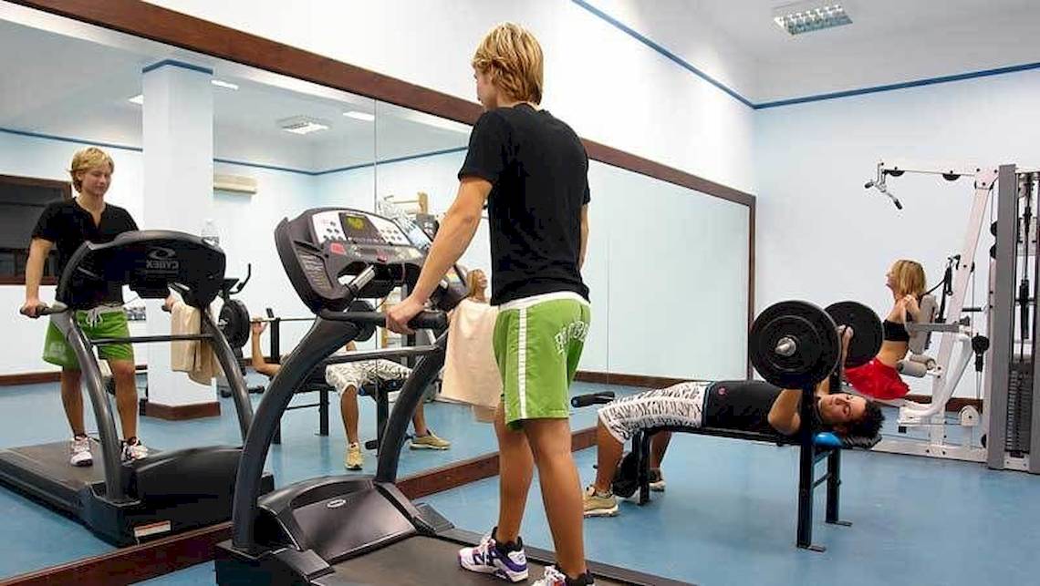 Fitnessstudio im Jaz Belvedere Resort mit Personen, die auf Laufband und Hantelbank trainieren.