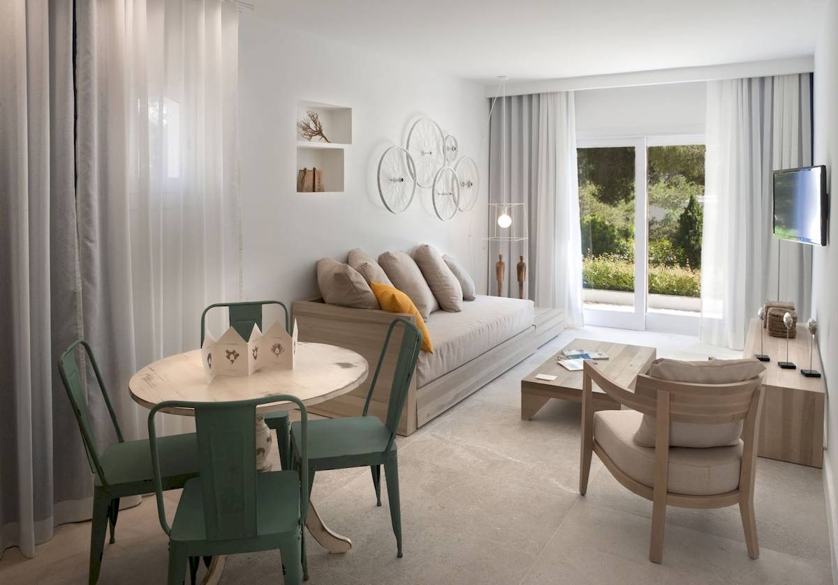 Hotel Paraiso de los Pinos Wohnzimmer mit Sofa, Tisch und Fernseher.