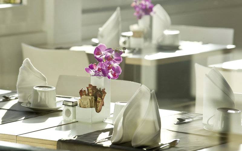 Ein gedeckter Tisch im Restaurant des Tahiti Hotels mit einer Orchidee in einer Vase.