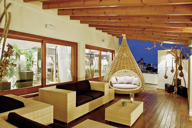 Lounge-Bereich des Tahiti Hotels mit Rattan-Sofas, Tisch und Hängesessel.