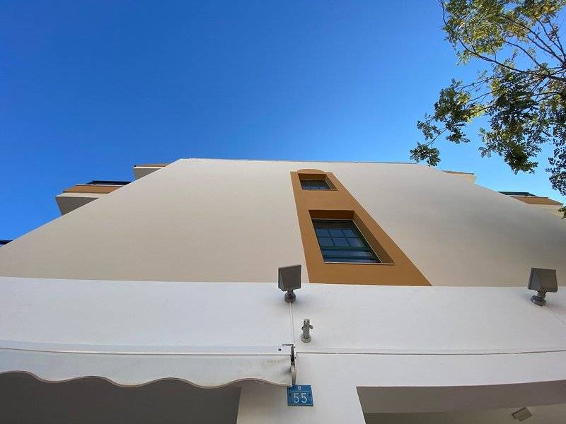 Außenansicht des Rosales Formentera Hotels mit weißer Fassade und braunen Fensterrahmen.