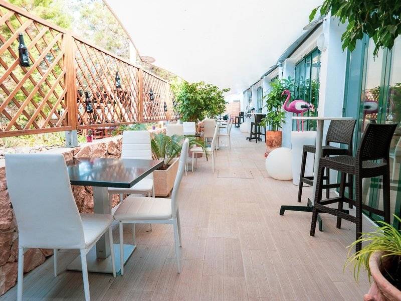 Rosales Formentera Hotel Terrasse mit weißen Stühlen, Tischen und Pflanzen.