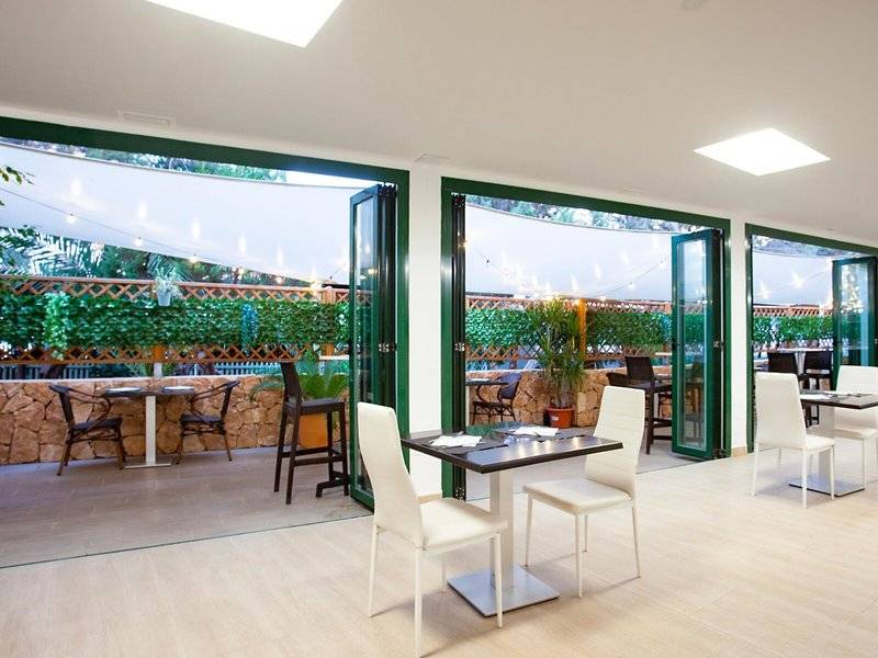 Innenbereich des Restaurants des Rosales Formentera Hotels mit Tischen, Stühlen und Pflanzen.