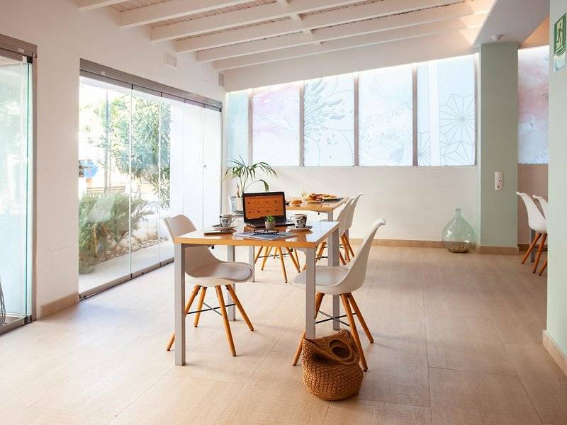 Rosales Formentera Hotel Innenraum mit Esstisch, Laptop und Pflanzen.