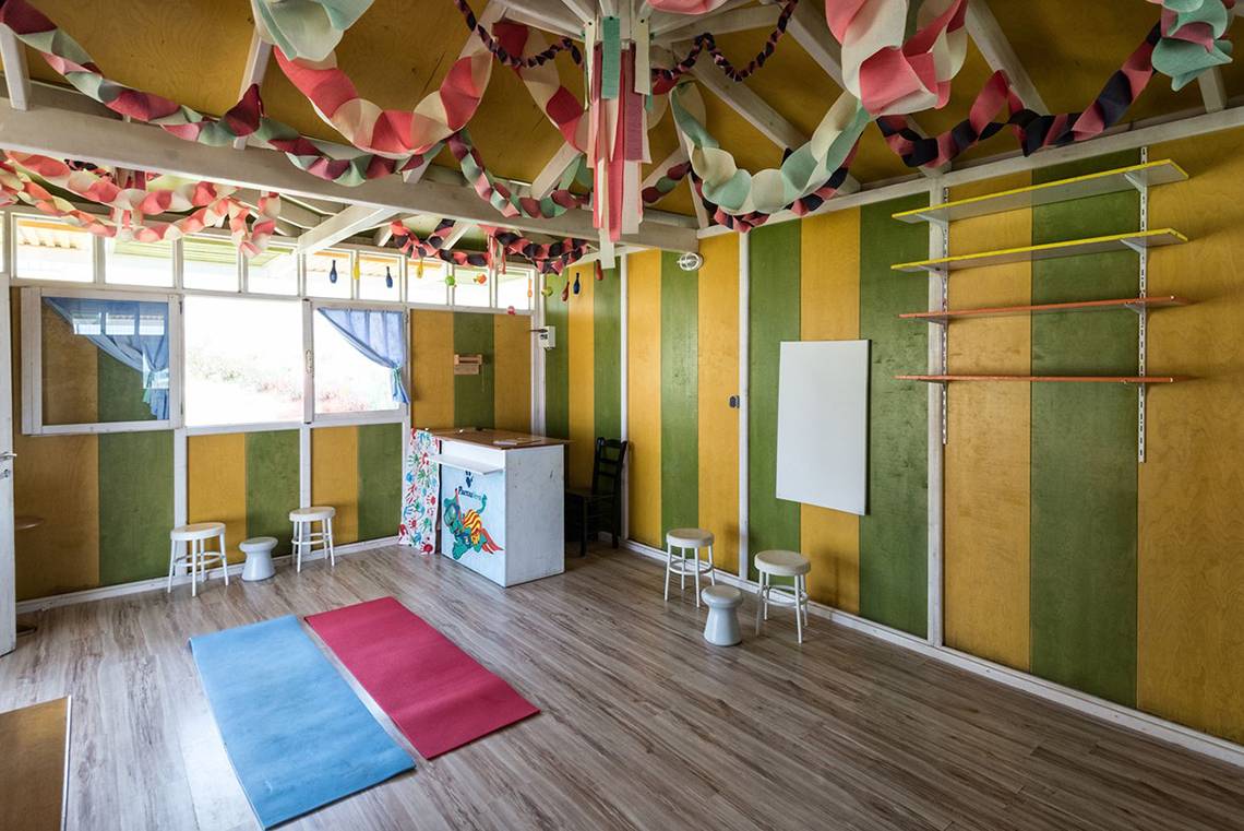 Innenraum des Eliros Mare Hotels mit farbigen Wänden, Yoga-Matten und Hockern.