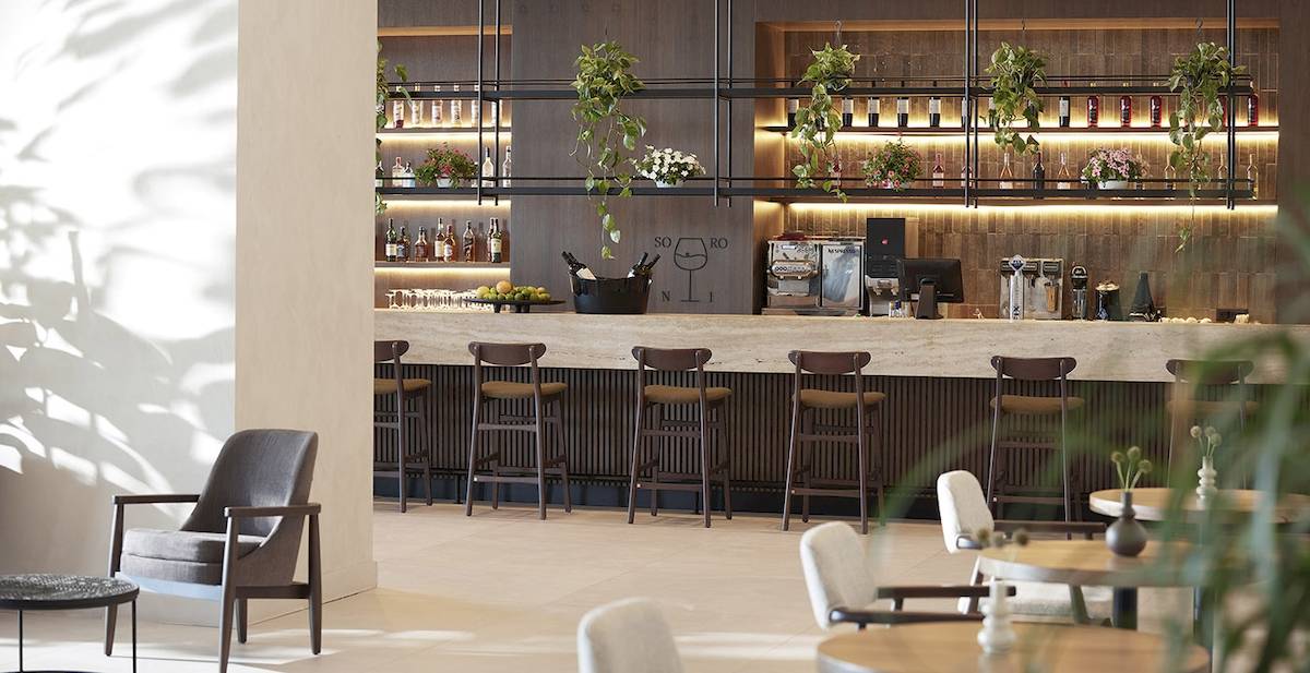 Barbereich im Helea Lifestyle Beach Resort mit gepolsterten Stühlen und Theke.