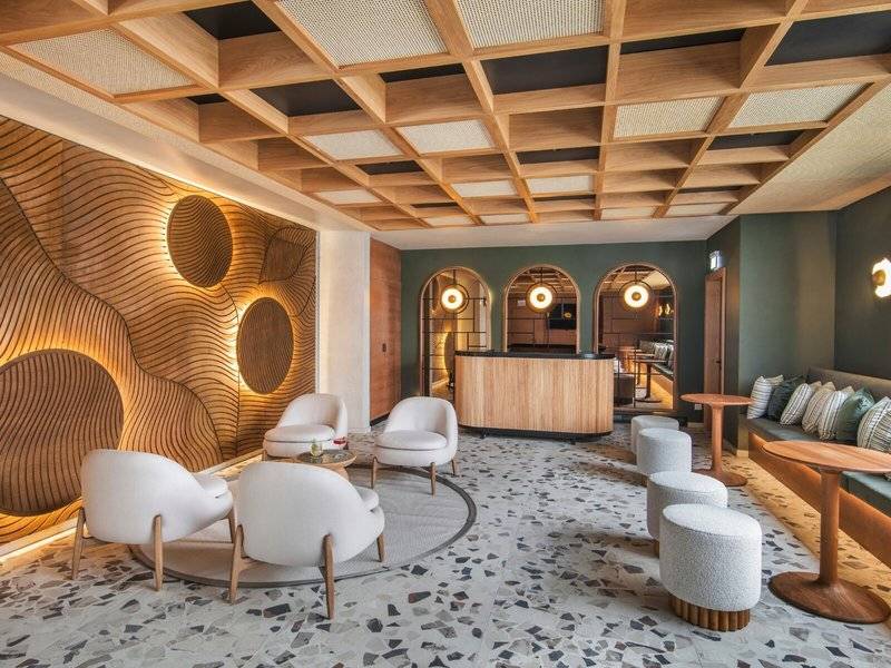 Loungebereich im Paradis Beachcomber Golf Resort & Spa mit weißen Sesseln, Holzelementen und grünen Wänden.