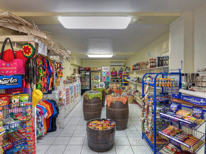Innenansicht eines bunten Ladens im Coconut Court Beach Hotel mit Regalen voller Snacks, bunten T-Shirts und dekorativen Gegenständen.