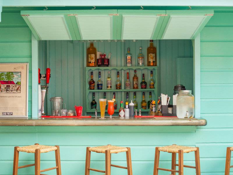 Cocktailbar im Sugar Bay Barbados mit grünen Wänden und einer Auswahl an Getränken.
