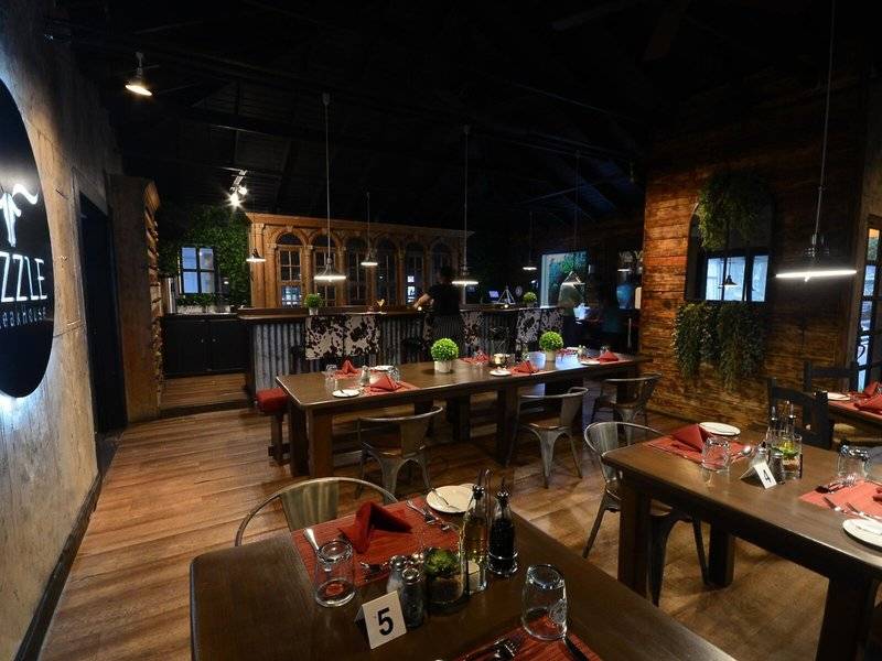 Innenansicht eines Restaurants mit rustikalem Design, Holztischen, Stühlen und dekorativen Elementen.
