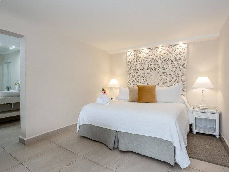 Schlafzimmer im Sugar Bay Barbados Hotel mit weißem Bett und Dekor.