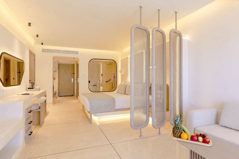 Innenansicht eines Hotelzimmers im Sunrise Anjum Resort mit Bett, Schreibtisch und Früchten auf einem Tablett.
