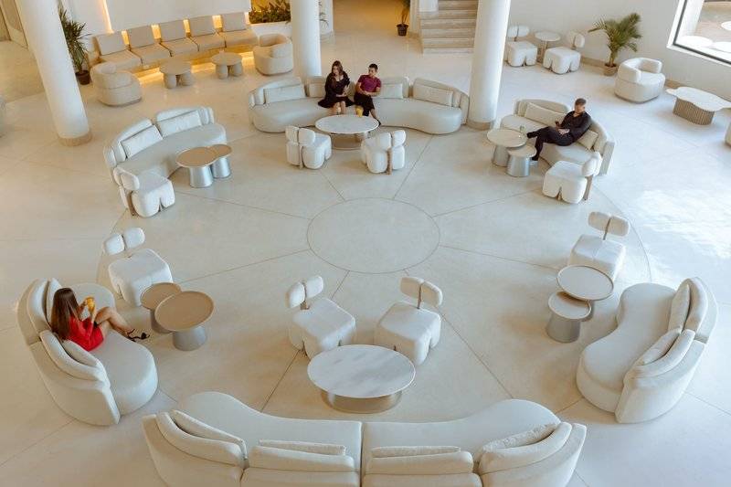 Lobby-Loungebereich im Sunrise Anjum Resort mit weißen Möbeln und mehreren Personen, die auf Sesseln und Tischen sitzen.