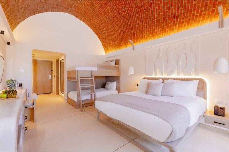 Innenansicht eines Zimmers im Sunrise Anjum Resort mit Doppelbett, Etagenbett und Früchten auf dem Tisch.