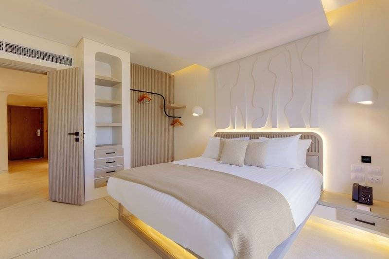 Schlafzimmer im Sunrise Anjum Resort mit weißem Bett und Einrichtung.