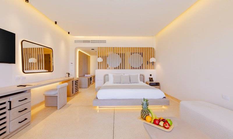 Ein modernes Hotelzimmer im Sunrise Anjum Resort mit einem Bett, einem Tisch mit Früchten und einem Spiegel.