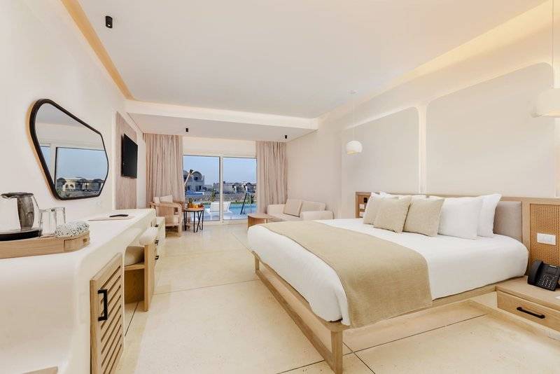 Innenansicht eines modernen Hotelzimmers im Sunrise Anjum Resort mit weißem Bett und Panoramafenster.