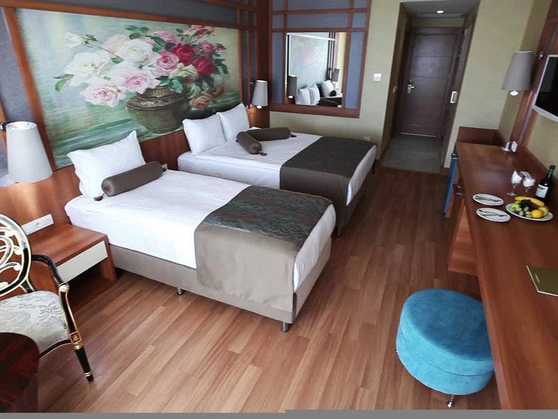 Ein Hotelzimmer mit zwei Betten, einem großen Gemälde, einer Kommode und einem Stuhl.
