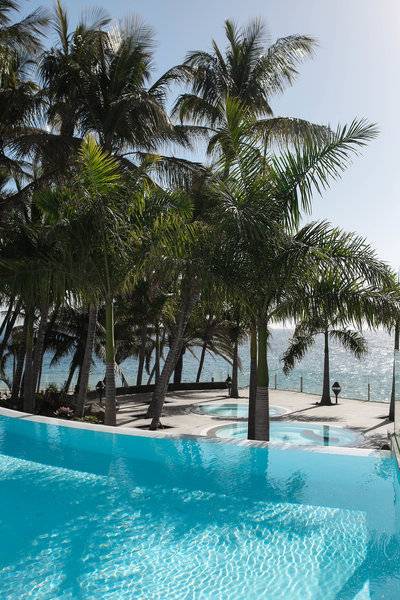 Fariones Hotel Außenpool mit Palmen und Meer im Hintergrund