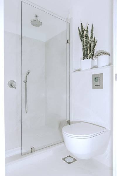 Ein Badezimmer mit einer Duschkabine und einem Toilettensitz in Weiß.