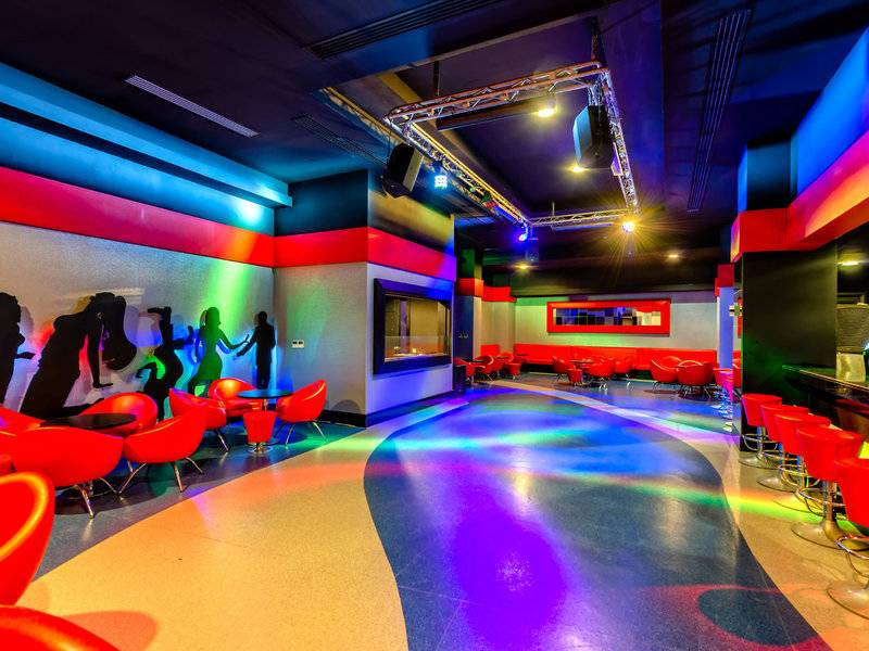 Disco-Bereich des Kirman Leodikya Resorts mit roten Stühlen und farbigen Lichtern.