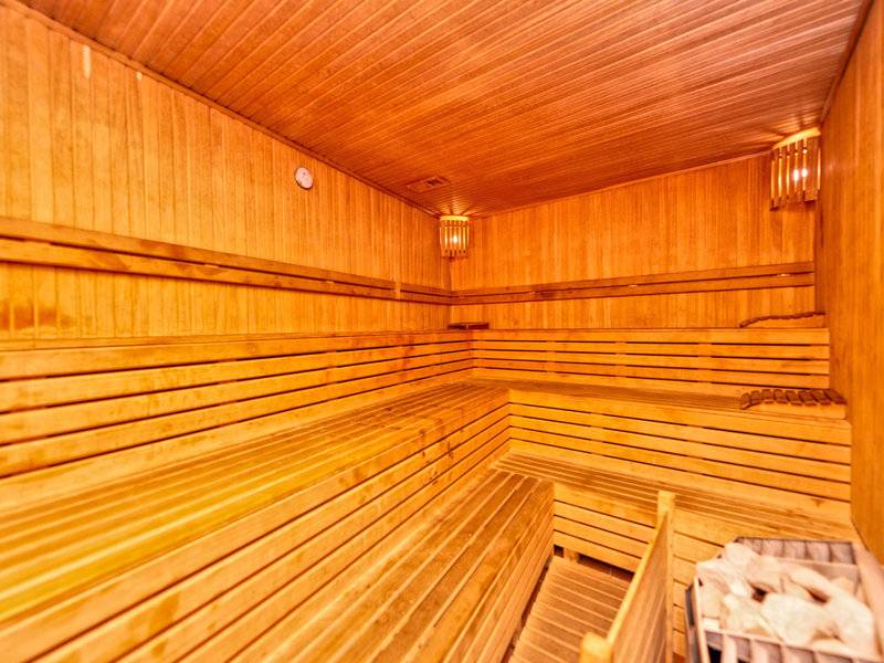Saunaraum im Kirman Leodikya Resort Hotel mit Holzbänken und einer Wanduhr.