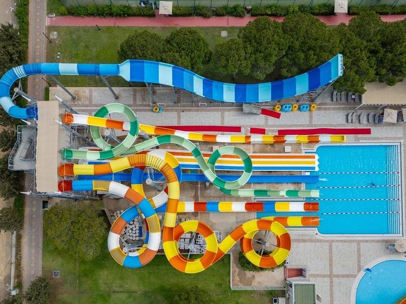 Luftaufnahme des Wasserparks im Ducale Lara Hotel mit mehreren Wasserrutschen und einem großen Pool.