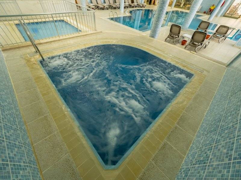 Innenpool des Ducale Lara Hotels mit fließendem Wasser und blauen Fliesen