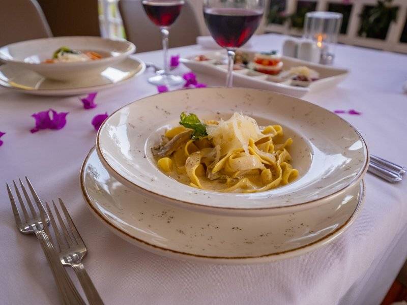 Tisch mit Essen im Ducale Lara Hotel mit einer Tasse Wein und Tellern mit Gerichten.