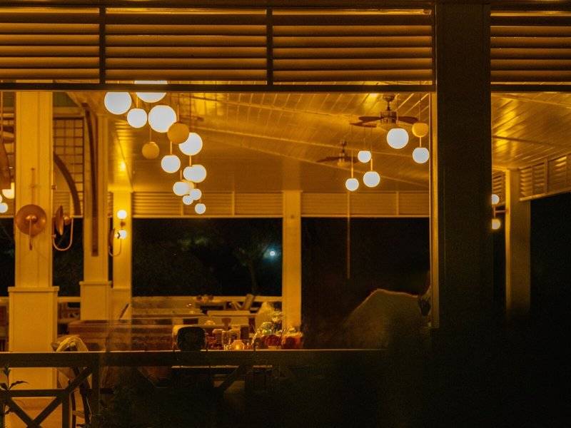 Veranda des Ducale Lara Hotels bei Nacht mit hängenden Lichtern und dunklem Hintergrund.