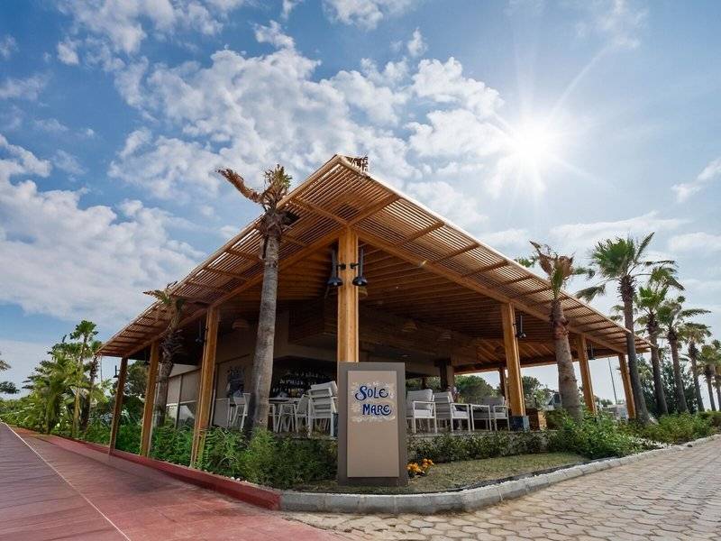 Außenterrasse des Ducale Lara Hotels mit Sonnenschirmen und Tischen im Freien.