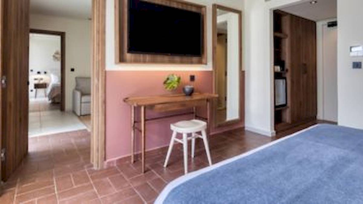 Innenansicht eines Zimmers im Domes Aulus Zante Hotel mit einem Bett, Schreibtisch und Fernseher