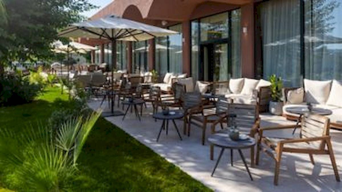 Terrasse des Domes Aulus Zante Hotels mit Tischen, Stühlen und Sonnenschirmen.