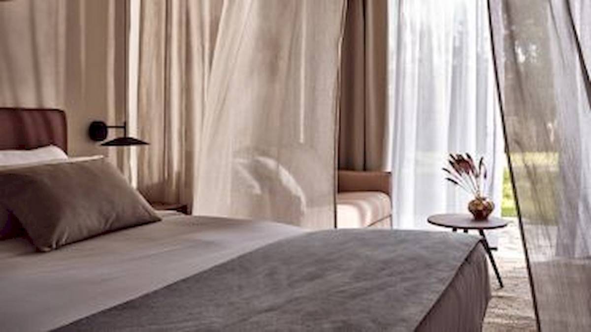 Schlafzimmer im Domes Aulus Zante Hotel mit Bett, Kopfteil, Kissen und Tisch mit Vase.