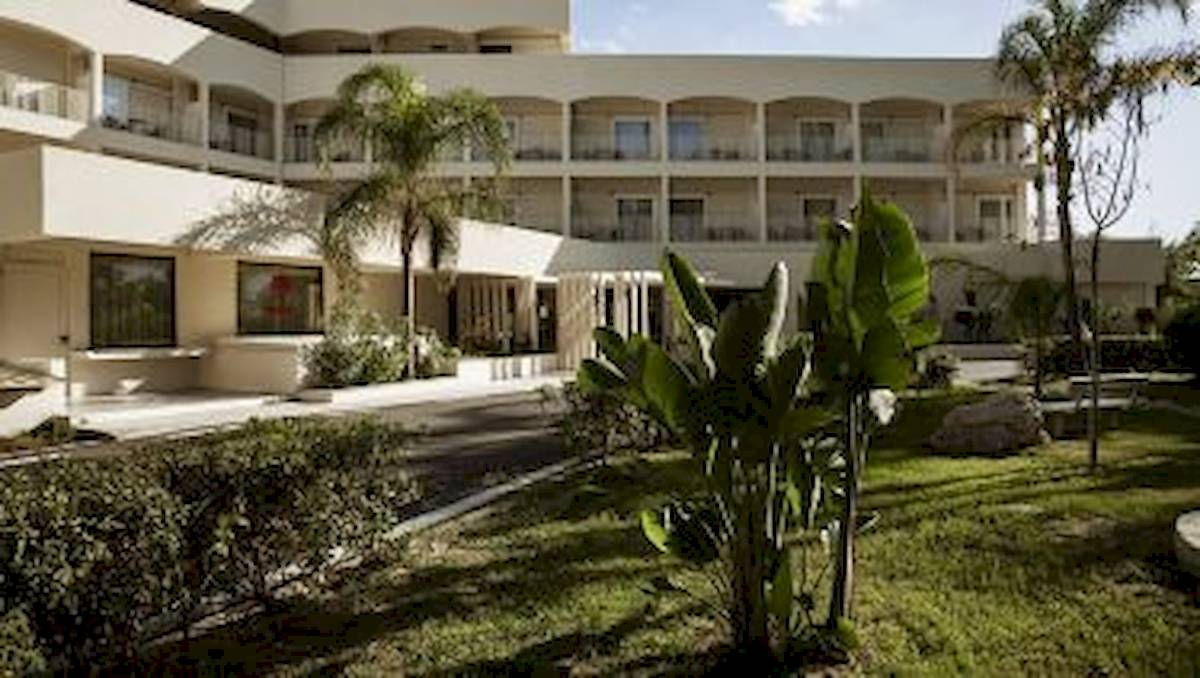Außenansicht des Domes Aulus Zante Hotels mit mehreren Stockwerken und Gärten davor.