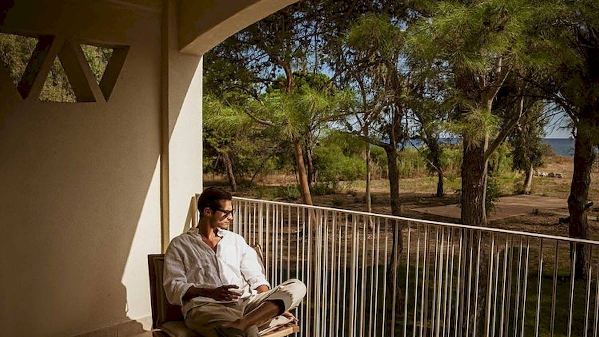 Ein Mann sitzt auf einem Stuhl auf der Balkon im Domes Aulus Zante Hotel.