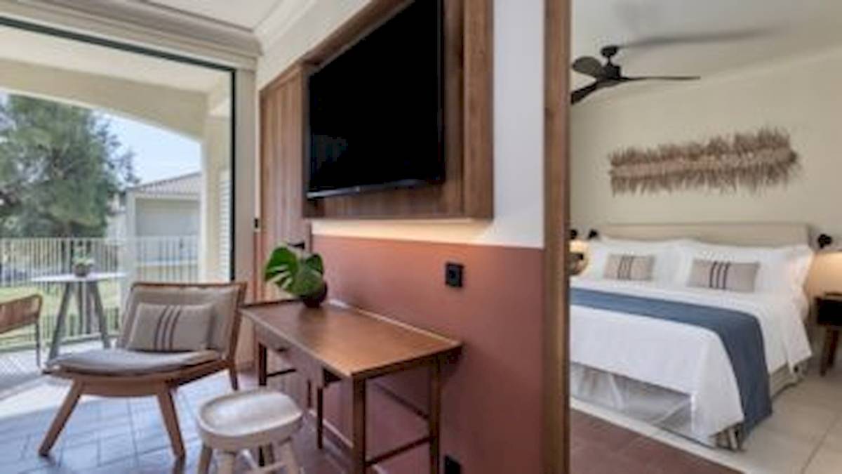 Ein modernes Hotelzimmer mit Balkon, Fernseher und bequemem Bett im Domes Aulus Zante.