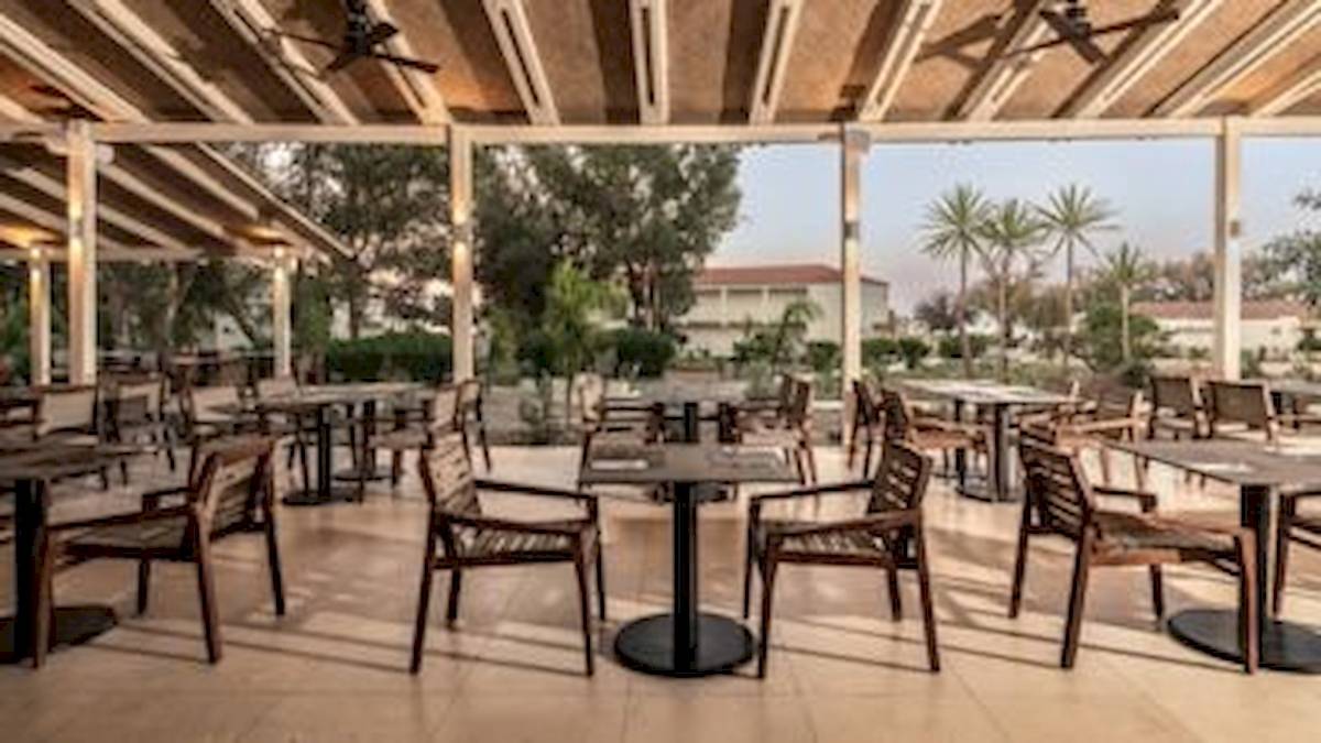 Terrasse des Domes Aulus Zante Hotels mit Tischen und Stühlen unter einer Überdachung.