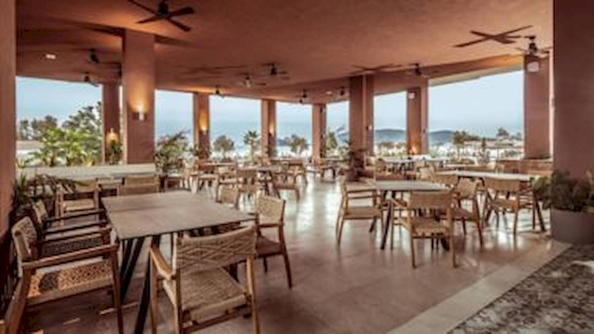 Innenbereich des Domes Aulus Zante Hotels mit mehreren Tischen und Stühlen und Blick auf das Meer.