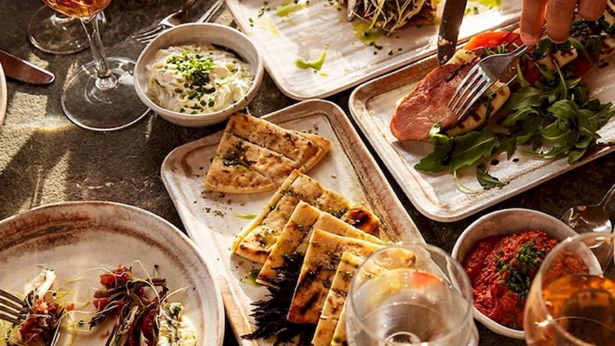 Verschiedene Speisen auf dem Tisch im Domes Aulus Zante, einschließlich Fleisch, Gemüse und Dips.