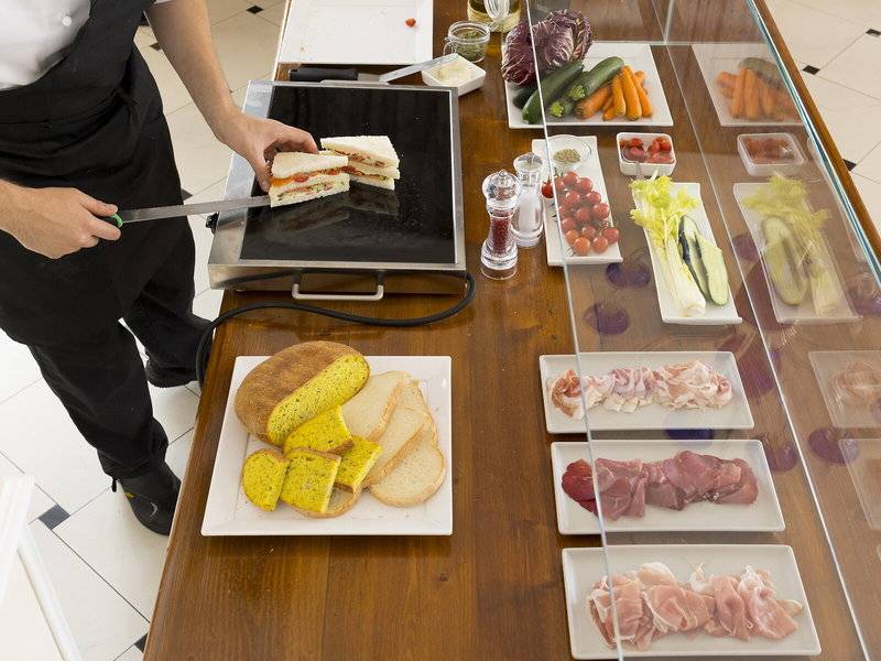 Ein Kellner im Baia Imperiale Hotel schneidet ein Sandwich auf einem Buffettisch.
