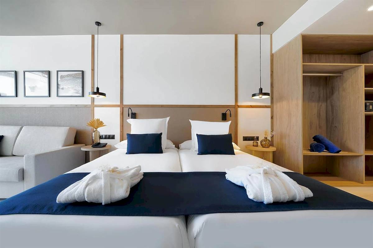 Doppelbettzimmer im H10 Costa Mogan Hotel mit weißen Möbeln und blauen Kissen