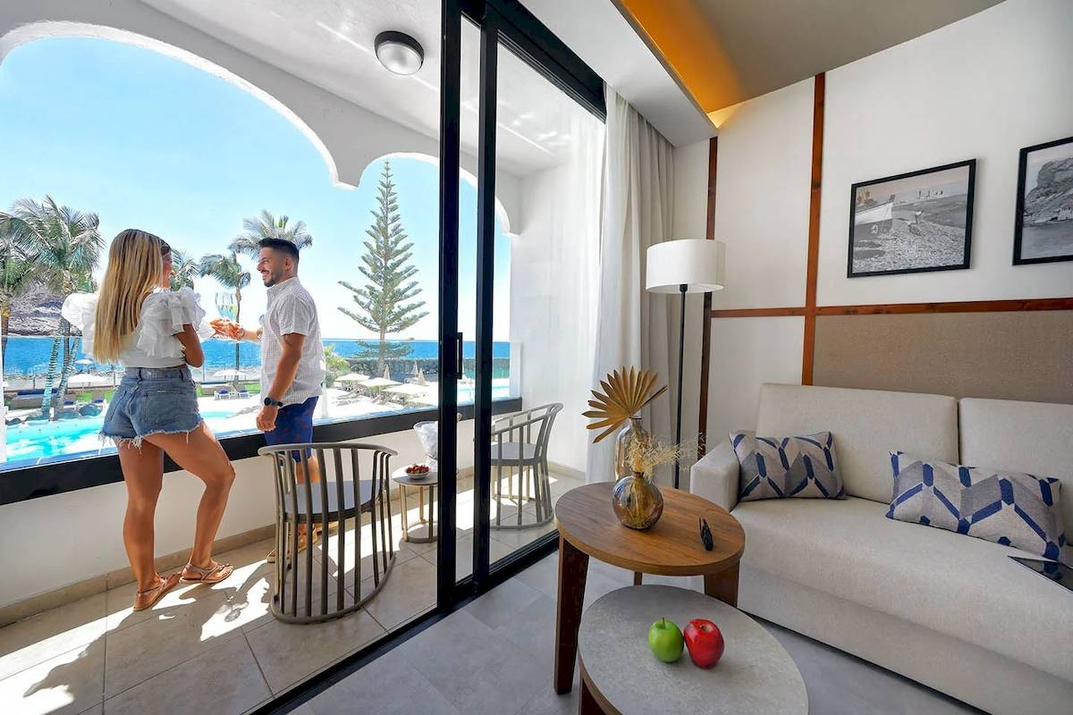 Paar auf dem Balkon des H10 Costa Mogan mit Blick auf den Ozean und Palmen