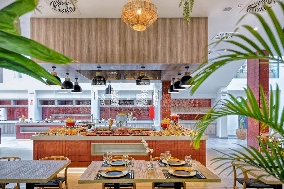 Innenansicht des Restaurants im H10 Costa Mogan Hotel mit Buffet, Tischen und Stühlen.
