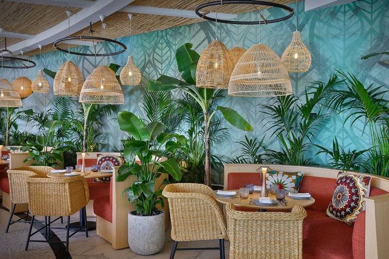 Innenraum des Restaurants im W Dubai - Mina Seyahi mit hängenden Lampen und Pflanzen.