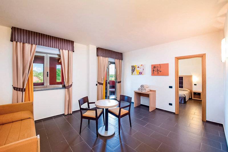 Hotelzimmer im VOI Baia di Tindari Resort mit Tisch, Stühlen und Bett.