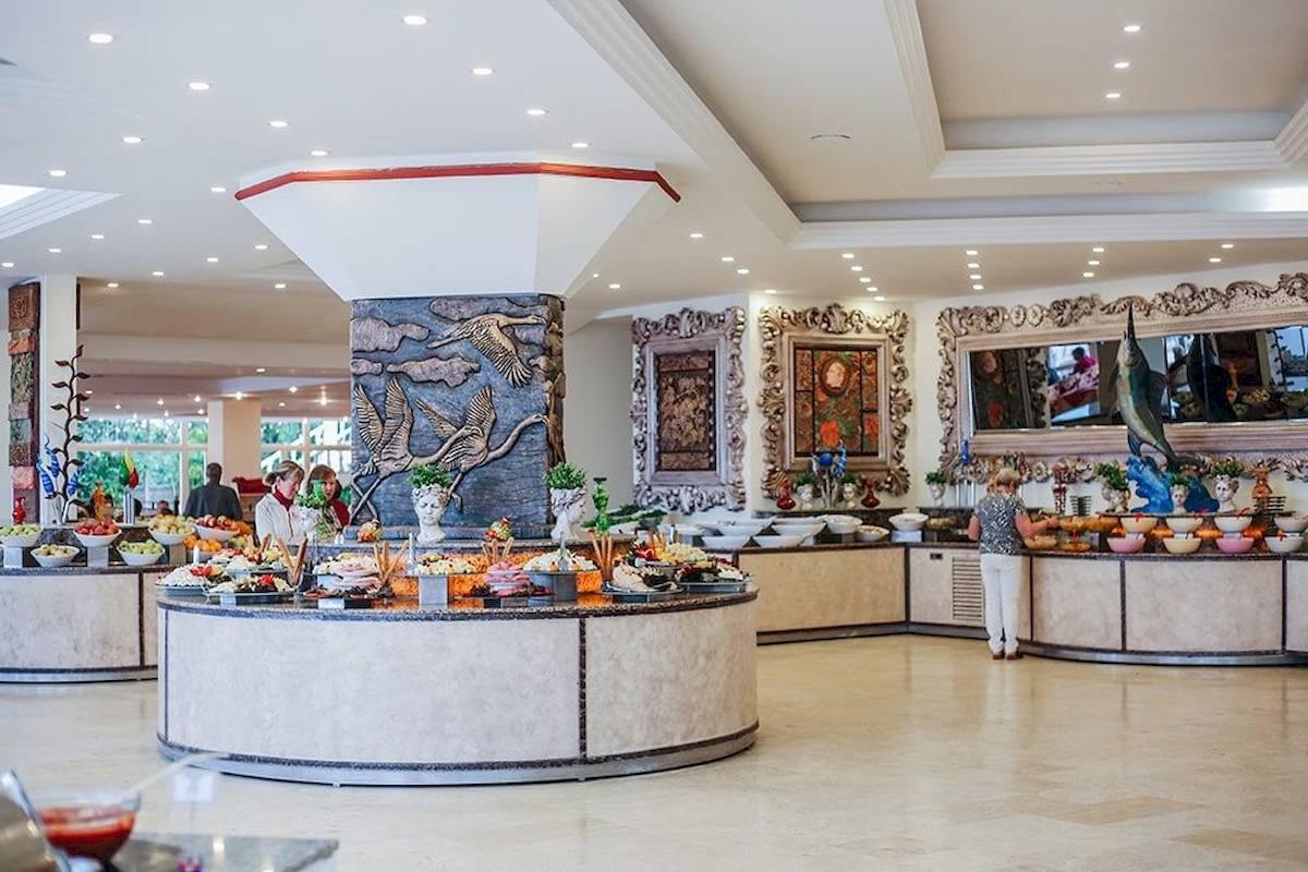 Buffetbereich im Cesars Side Hotel mit verschiedenen Speisen und einer Person, die bedient.