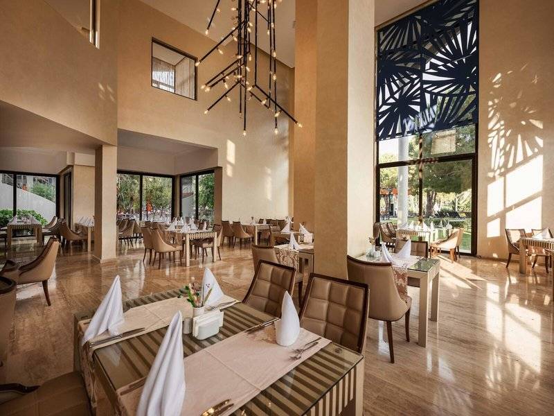 Innenansicht des Restaurants im Megasaray Resort Side mit gedeckten Tischen und dekorativen Kronleuchtern.
